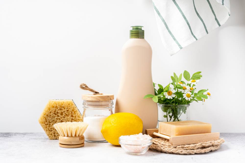Produits de nettoyage naturels : éponge, brosse en bois, citron, bicarbonate et savon